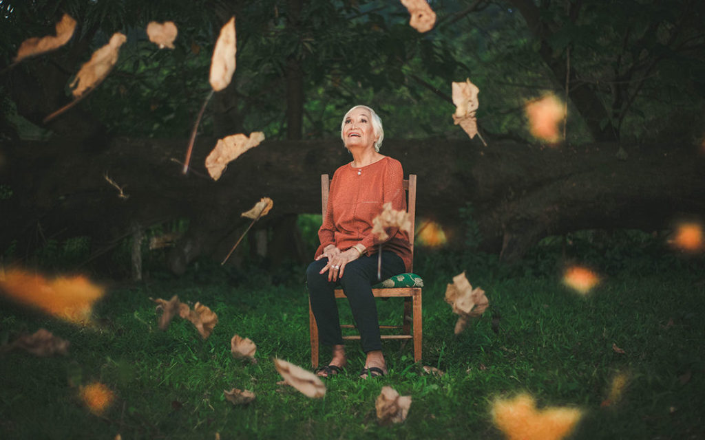 old lady on chair in yard with leaves